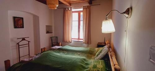 a room with a bed with a lamp and a window at Karádi Vendégház in Háromhuta