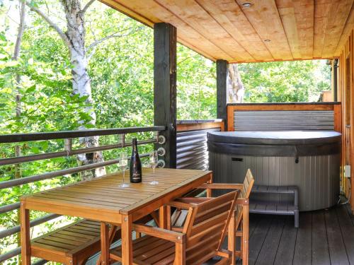 a wooden table and chairs on a deck with a hot tub at Peris Lodge - Uk47606 in Caernarfon