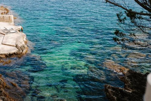 a view of the clear blue water next to a cliff at Hôtel Le Provençal - Rénové en 2025 - Bord de Mer in Hyères