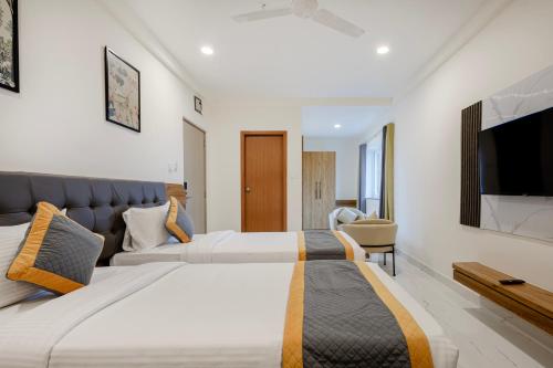 two beds in a hotel room with a flat screen tv at Lemonridge Hotels IDPL Balanagar in Hyderabad