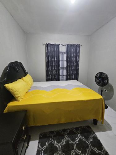 a bedroom with a bed with a yellow blanket at Lovely 4BR house in Maypen in Curatoe Hill