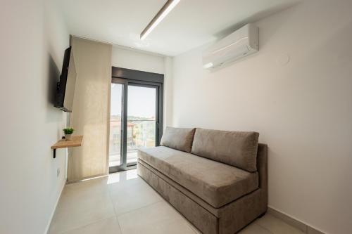 a living room with a couch and a window at Chalkidiki Suites in Paralia Dionysiou