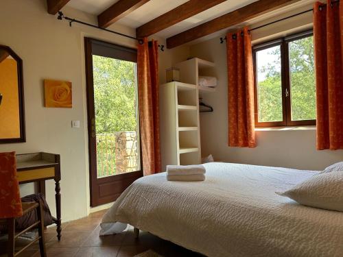 Un dormitorio con una cama, un escritorio y ventanas. en Beau mas cévenol avec piscine, en Corbés
