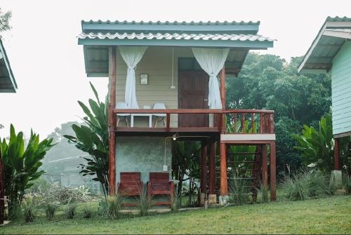 ein Haus mit einer Terrasse mit zwei Stühlen und einer Veranda in der Unterkunft Doi Piang Dao Farm in Ban Tham