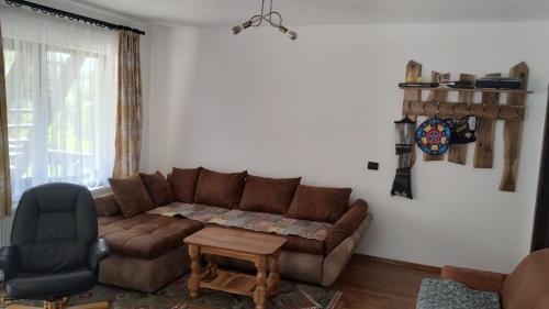 a living room with a brown couch and a chair at Casa Noastră in Vidra