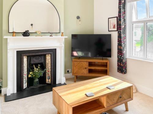 a living room with a fireplace and a tv at Poppy Cottage in Eryholme
