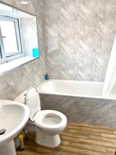 a bathroom with a toilet and a sink and a tub at Step4 Home in Rainham