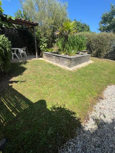 a garden with a table and a bench in a yard at studio bord de mer in Ver-sur-Mer