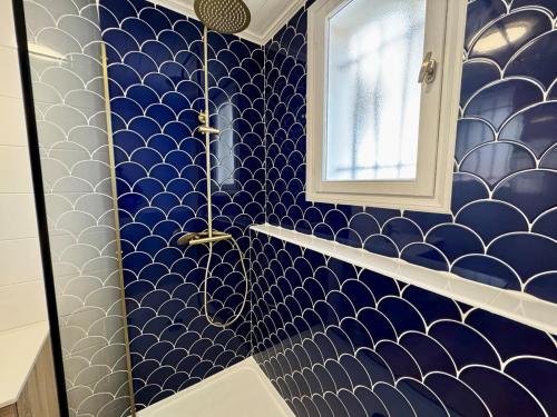 ein Bad mit blau und weiß gefliesten Wänden und einer Dusche in der Unterkunft Évasion Marine à 2 pas du Port in Saint-Gilles-Croix-de-Vie