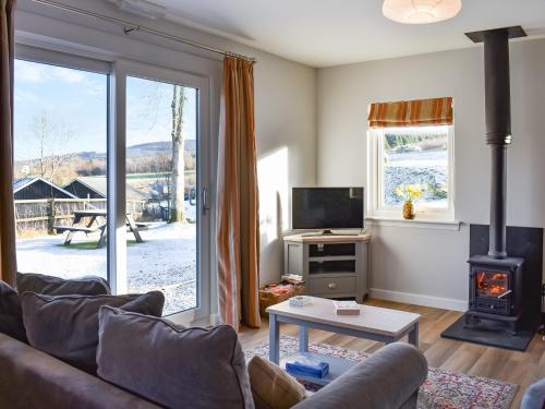 a living room with a couch and a stove at Rannoch Lodge in Aberfeldy