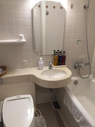 a bathroom with a sink and a toilet and a tub at Hotel Monterey Nagasaki in Nagasaki