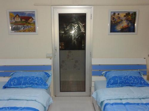 a bedroom with two beds and a door to a window at Smart Residence@Muengthongthani in Nonthaburi