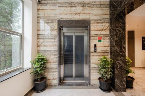 a lobby with two potted plants in front of a elevator at Lemonridge Hotels IDPL Balanagar in Hyderabad