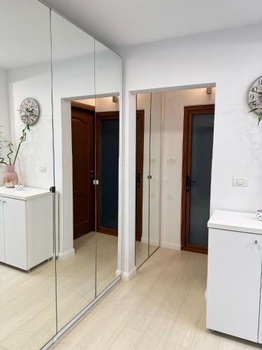 a bathroom with glass walls and a sink and a mirror at Apartament Faleza Nord in Constanţa