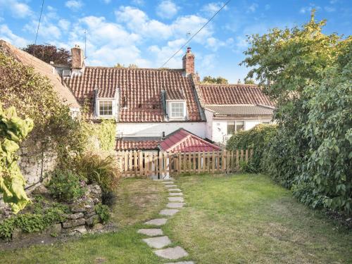 a house with a wooden fence and a yard at Darla Cottage in Thornton Dale