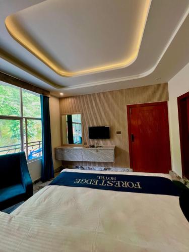 a bedroom with a large bed and a television at Forest Edge Hotel in Murree