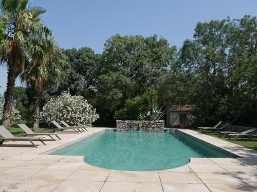 une piscine avec des chaises longues et des arbres dans l'établissement Domaine de Livière-Haute Narbonne, à Narbonne