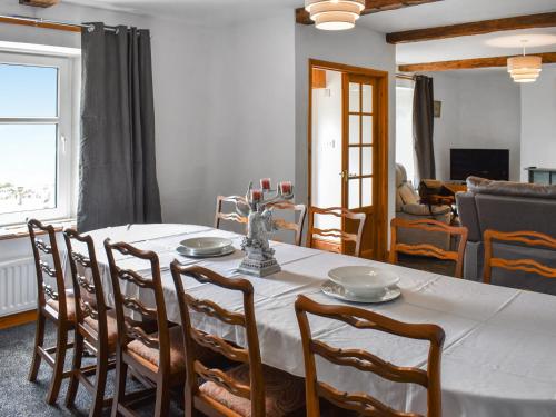 a dining room table with a white table cloth and chairs at Uk46833 - Low Hollas Farmhouse in Threlkeld