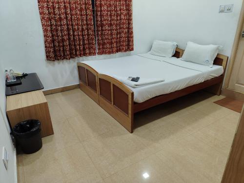 a small bedroom with a bed with white sheets at Swarna Sudarshan Service Apartment @ Adyar chennai in Chennai