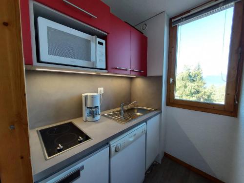 une petite cuisine avec un évier et un micro-ondes dans l'établissement Studio confortable pour 3 avec balcon et animaux acceptés à La Plagne - FR-1-353-9, à La Plagne