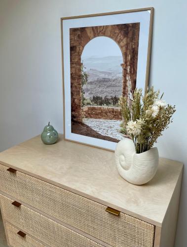 a picture on top of a dresser with a vase at La Sénéchalerie in Chasselay