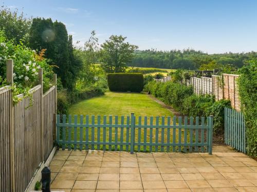 a garden with a blue fence and a yard at Longford Cottage in Haven Street