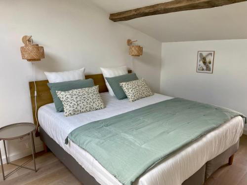 a bedroom with a large bed with green and white pillows at La Sénéchalerie in Chasselay