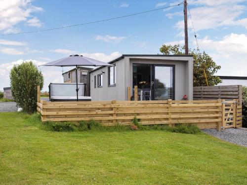 a small house with a wooden fence and an umbrella at Uk46570 - Awel Y Mor in Holyhead