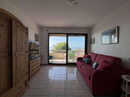 un salon avec un canapé rouge et un balcon dans l'établissement Studio cosy au Lavandou avec terrasse et parking - FR-1-308-73, au Lavandou