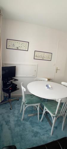 une chambre avec deux tables et des chaises ainsi qu'une télévision dans l'établissement La Goélette Beau duplex A 150 m du centre ville et 400m de la plage de l'écluse, à Dinard