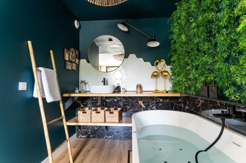 オードンジュにあるLa Cachette des amoureux balnéo en duoの緑の壁のバスルーム(バスタブ付)