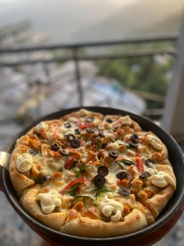a pizza with olives and peppers in a pan at Forest Edge Hotel in Murree