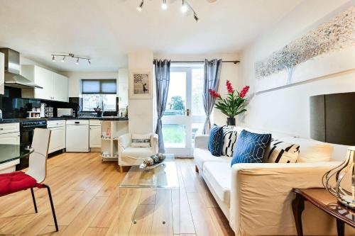 a living room with a white couch and a kitchen at Destination London Docklands Riverside in London