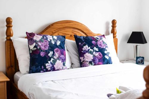 a bed with purple and purple pillows on it at Riverside Townhouse with Private Garden in London