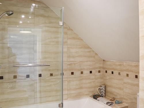 a shower with a glass door in a bathroom at Lon Lwyd Isaf in Pentraeth