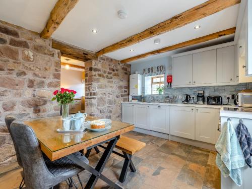 a kitchen with white cabinets and a wooden table at The Stables - Uk46731 in Wootton