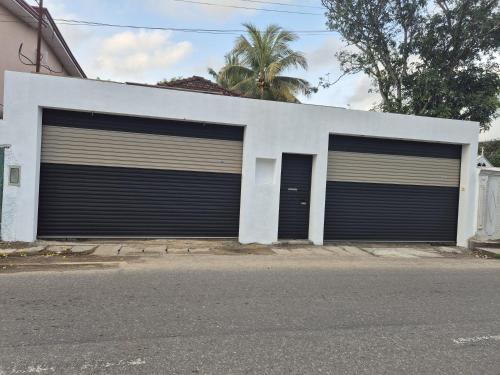 two garage doors on a white building on a street at Comfortable Stay in Colombo in Rajagiriya