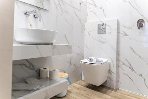 a white bathroom with a sink and a toilet at Hotel Diana in Koroni