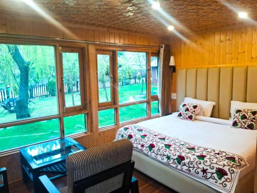 une chambre avec un lit, un bureau et des fenêtres dans l'établissement River Retreat Resort, à Pahalgām