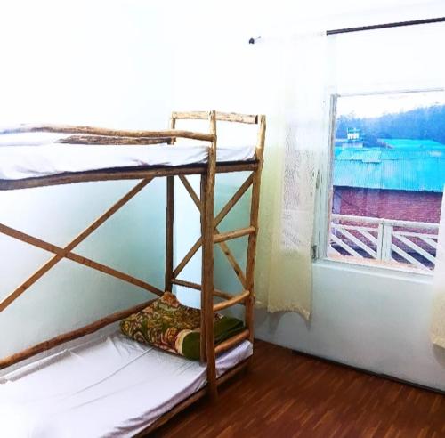 two bunk beds in a room with a window at Buddies Stay Café Community in Manāli