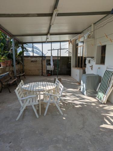 a patio with two white chairs and a table at Casa Aurora - Vacanze nel cuore del Salento in Scorrano