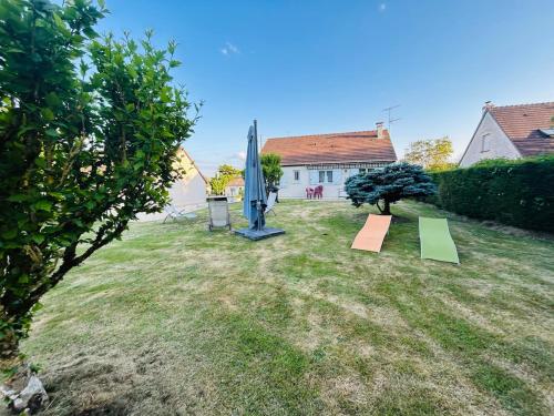 a garden with a umbrella and a surfboard in the grass at GÎTE Au 21 Loveroom in Beaumont-la-Ronce