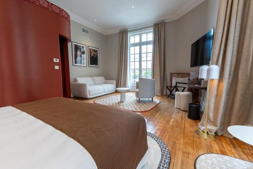 a bedroom with a bed and a living room at Hôtel des Arts in Angoulême