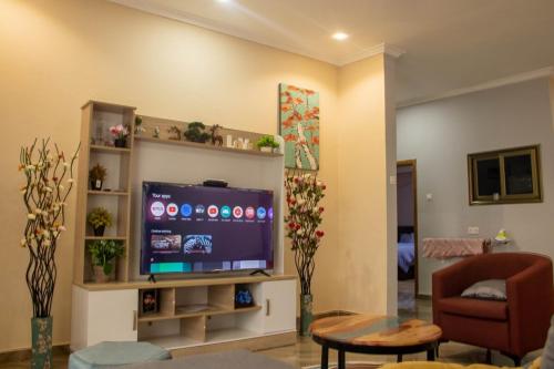 a living room with a flat screen tv and a chair at FranGee gold house with cool breeze & solar backup in Kpomkpo
