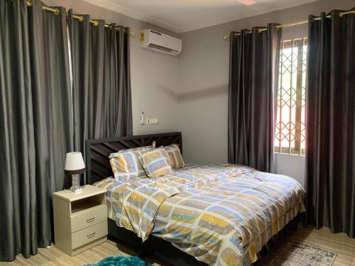 a bedroom with a bed and a window with curtains at FranGee gold house with cool breeze & solar backup in Kpomkpo