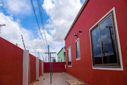 a red building with a window on the side of it at FranGee gold house with cool breeze & solar backup in Kpomkpo