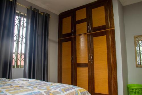 a bedroom with a wooden cabinet and a bed at FranGee gold house with cool breeze & solar backup in Kpomkpo