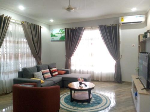 a living room with a couch and a table at FranGee gold house with cool breeze & solar backup in Kpomkpo