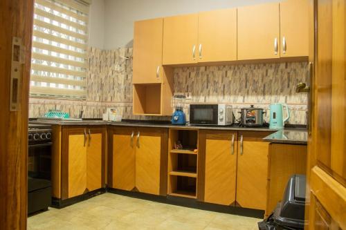 a kitchen with wooden cabinets and a microwave at FranGee gold house with cool breeze & solar backup in Kpomkpo
