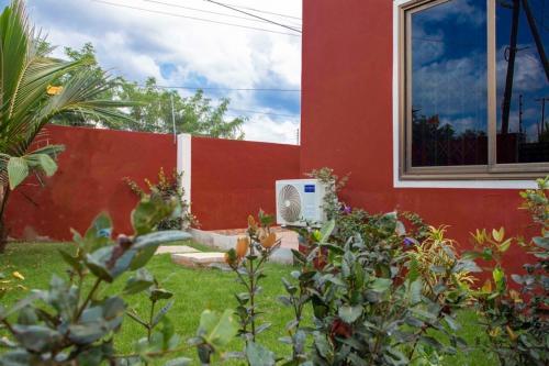 a red building with a fan in the yard at FranGee gold house with cool breeze & solar backup in Kpomkpo